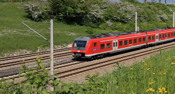 Regiobahn fährt auf Schienen durch eine grüne Landschaft. 
