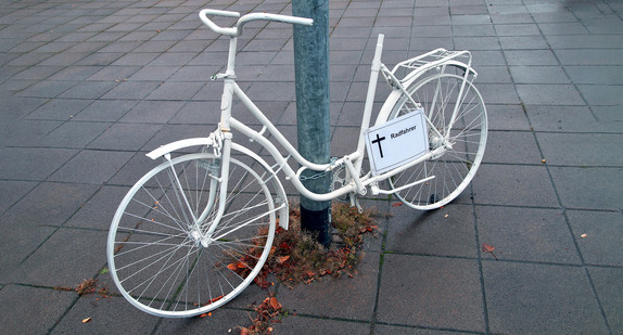 Ein weißes Fahrrad steht an einem Laternenmast.