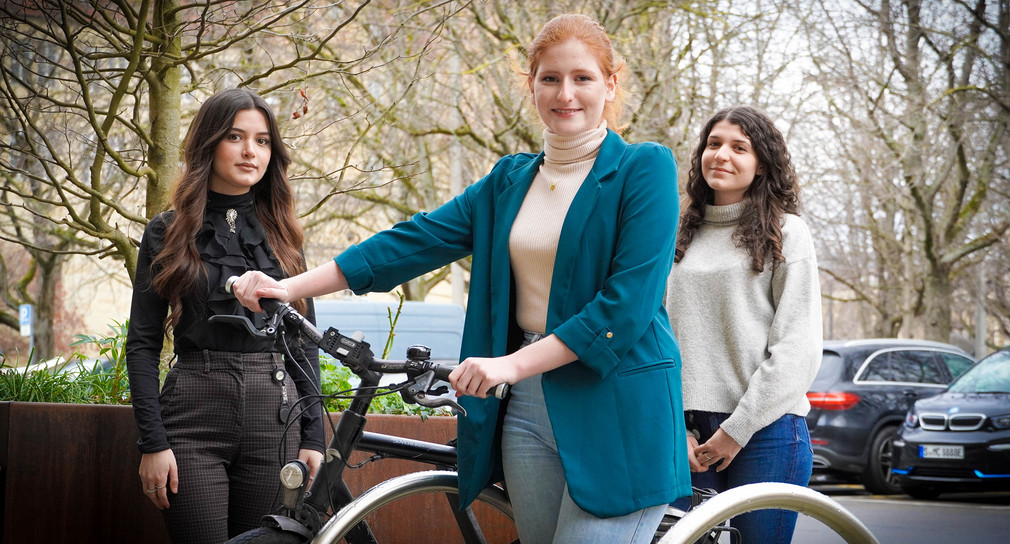 Drei Frauen stehen um ein Fahrrad nebeneinander.