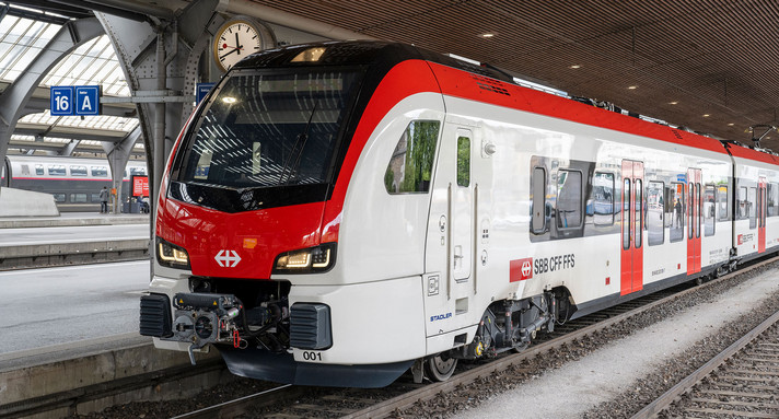 Ein roter Zug steht an einem Bahnsteig.