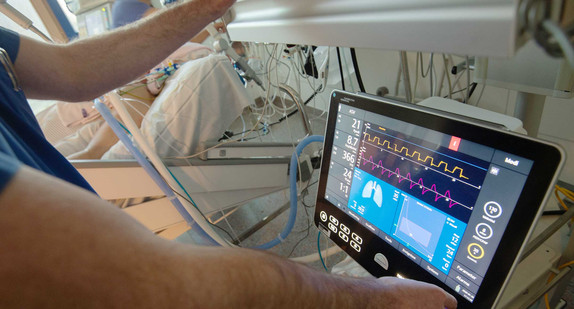 Ein Arzt bedient eine Beatmungsmaschine auf einer Intensivstation. 