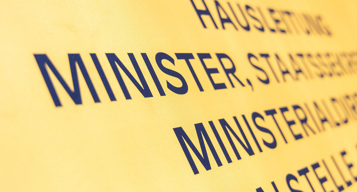 Ein Schild an der Wand mit den Namen Hausleitung und Minister.