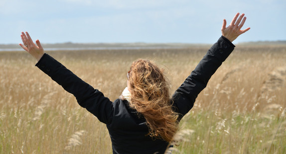 Frau steht in einem Feld und breitet die Arme aus (Bild: Fotolia.com/ The Photos)