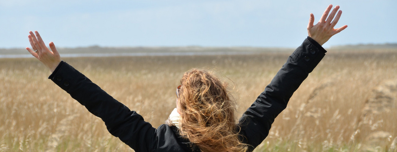 Frau steht in einem Feld und breitet die Arme aus (Bild: Fotolia.com/ The Photos)