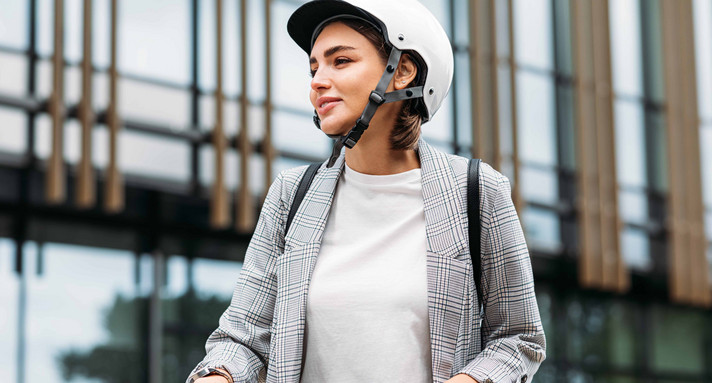 Frau im weißen Fahrradhelm hält einen Lenker eines Elektrorollers und schaut weg
