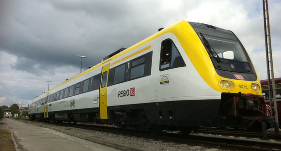 Gelb-weißer Zug steht auf einem Gleis.