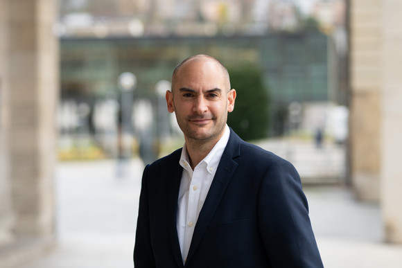 Porträtbilder Minister Dr. Danyal Bayaz Finanzminister Danyal Bayaz steht am Schlossplatz in Stuttgart, im Hintergrund ist moderne Architektur sowie ein Teil des Platzes zu sehen.