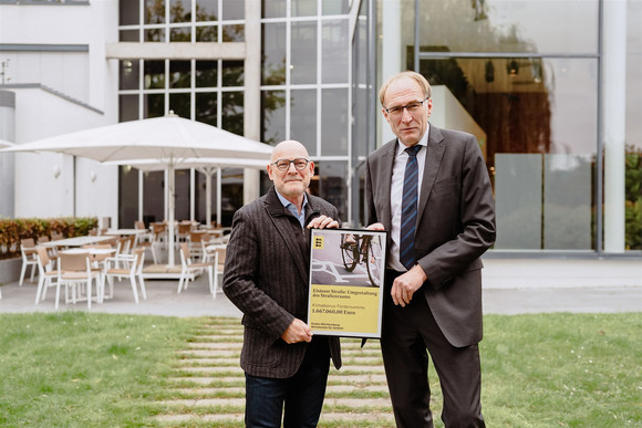 Verkehrsminister Winfried Hermann und Prof. Dr. Martin Haag, Baubürgermeister der Stadt Freiburg, mit einem Förderbescheid für die Maßnahme „Elsässer Straße: Umgestaltung des Straßenraums“.