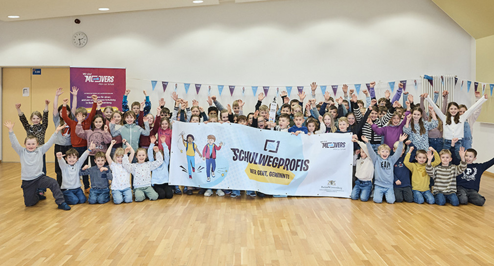 Viele Kinder freuen sich und halten ein Banner hoch.