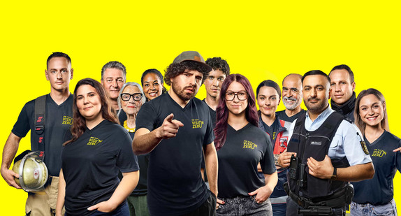 Ein Gruppenbild des Team Vison Zero. Zu sehen sind Feuerwehrleute, eine Rettungssanitäterin, ein Polizist, ein Fahrsicherheitstrainer, eine Fahrschullehrerin, Comedians, Moderator:innen und Bürger:innen verschiedenen Alters. 