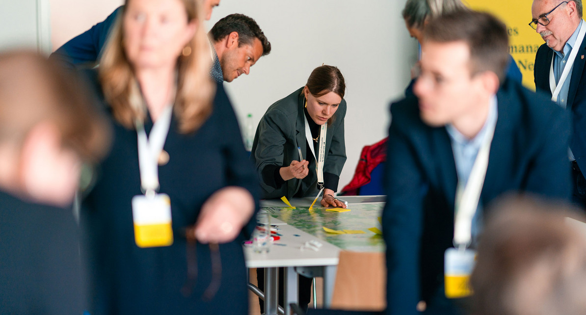 Eine Frau lehnt &uuml;ber einem Tisch und schreibt auf eine Karte.
