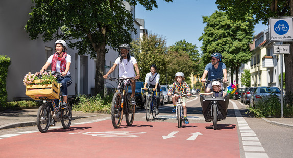 Mehrere Erwachsene und Kinder fahren Fahrrad in einer Fahrradstraße. 