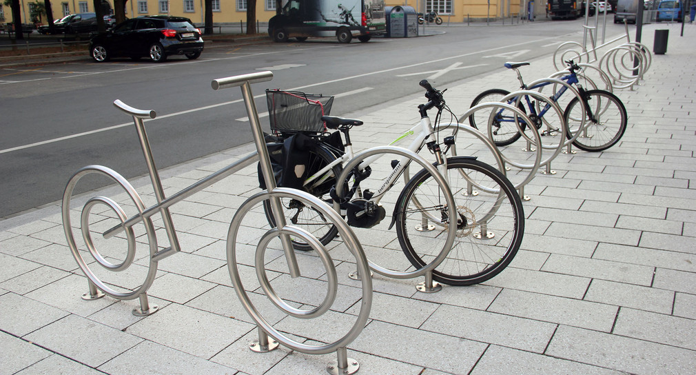 Fahrradräder stehen im Freien an Radständern angeschlossen.