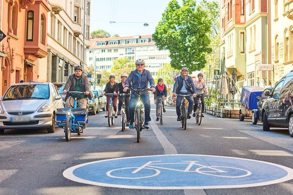 Verkehrsminister Hermann, Amtschef Frieß sowie Mitarbeiterinnen und Mitarbeiter des Landesradeln durch eine Fahrradstraße.