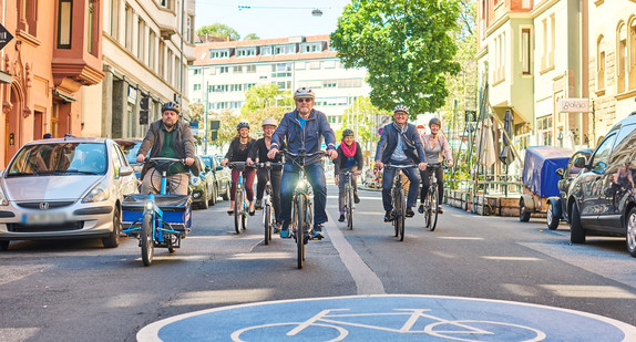 Verkehrsminister Hermann, Amtschef Frieß sowie Mitarbeiterinnen und Mitarbeiter des Landesradeln durch eine Fahrradstraße.