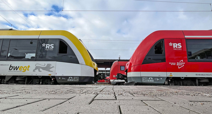 Zwei Züge stehen sich an einem Bahnsteig gegenüber.