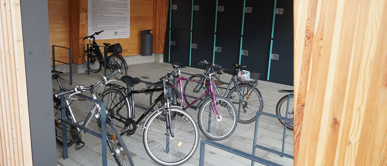 Mehrere Fahrräder stehen unter einem Dach angeschlossen an Fahrradständern.