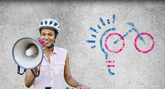 Eine Frau mit Fahrradhelm hält ein Megafon vor den Mund.