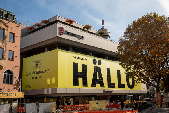 Imagekampagne Baden-Württemberg ist „THE LÄND“ Fassade mit der Aufschrift „Baden-Württemberg - THE LÄND“ unter dem Landeswappen sowie „THE LÄND sagt HÄLLO“ am Kaufhaus Breuninger in Stuttgart