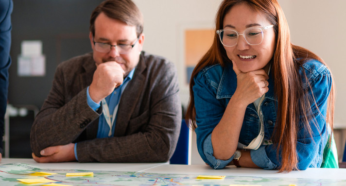 Eine Frau und ein Mann sitzen an einem Tisch und schauen auf Post-it Zettel.