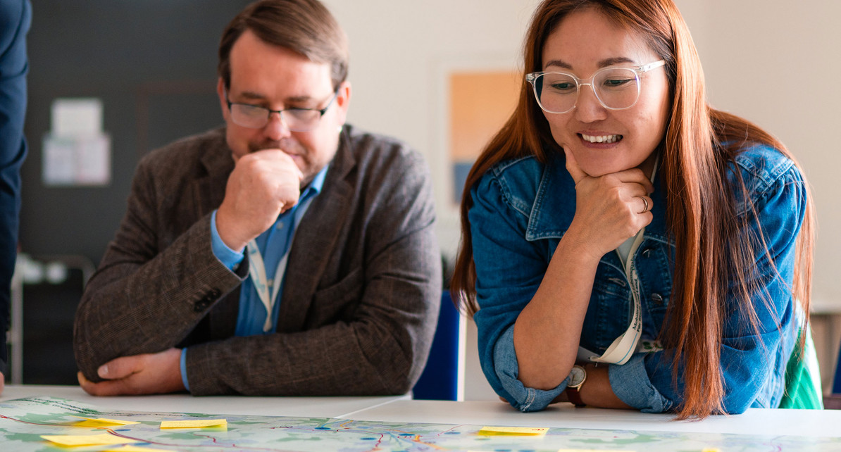 Eine Frau und ein Mann sitzen an einem Tisch und schauen auf Post-it Zettel.