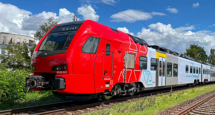 Ein roter Zug steht auf Gleisen.