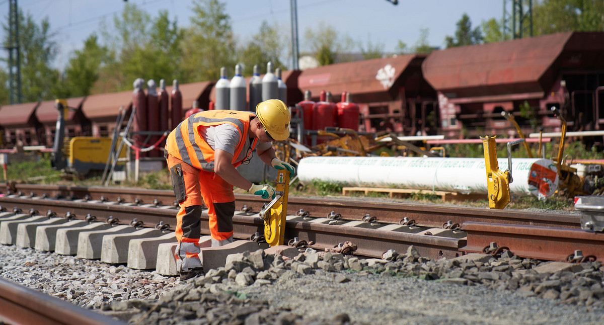 Ein Gleisarbeiter arbeitet an einer Schiene.