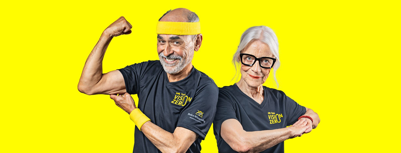 Ein Senior und eine Seniorin posieren sportlich vor einem gelben Hintergrund