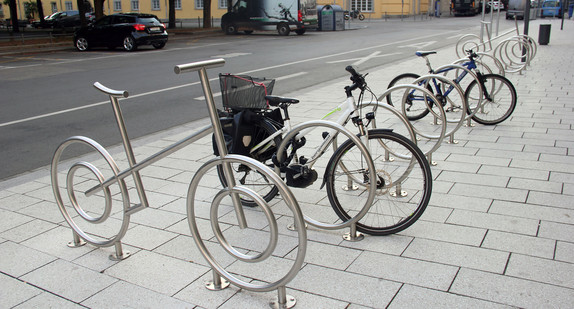Fahrradräder stehen im Freien an Radständern angeschlossen.