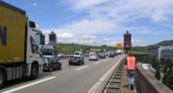 Fahrende LKWs und Autos auf einer Autobahn, Person läuft mit Warnweste am Seitenrand (Bild: Straßenverkehrszentrale)