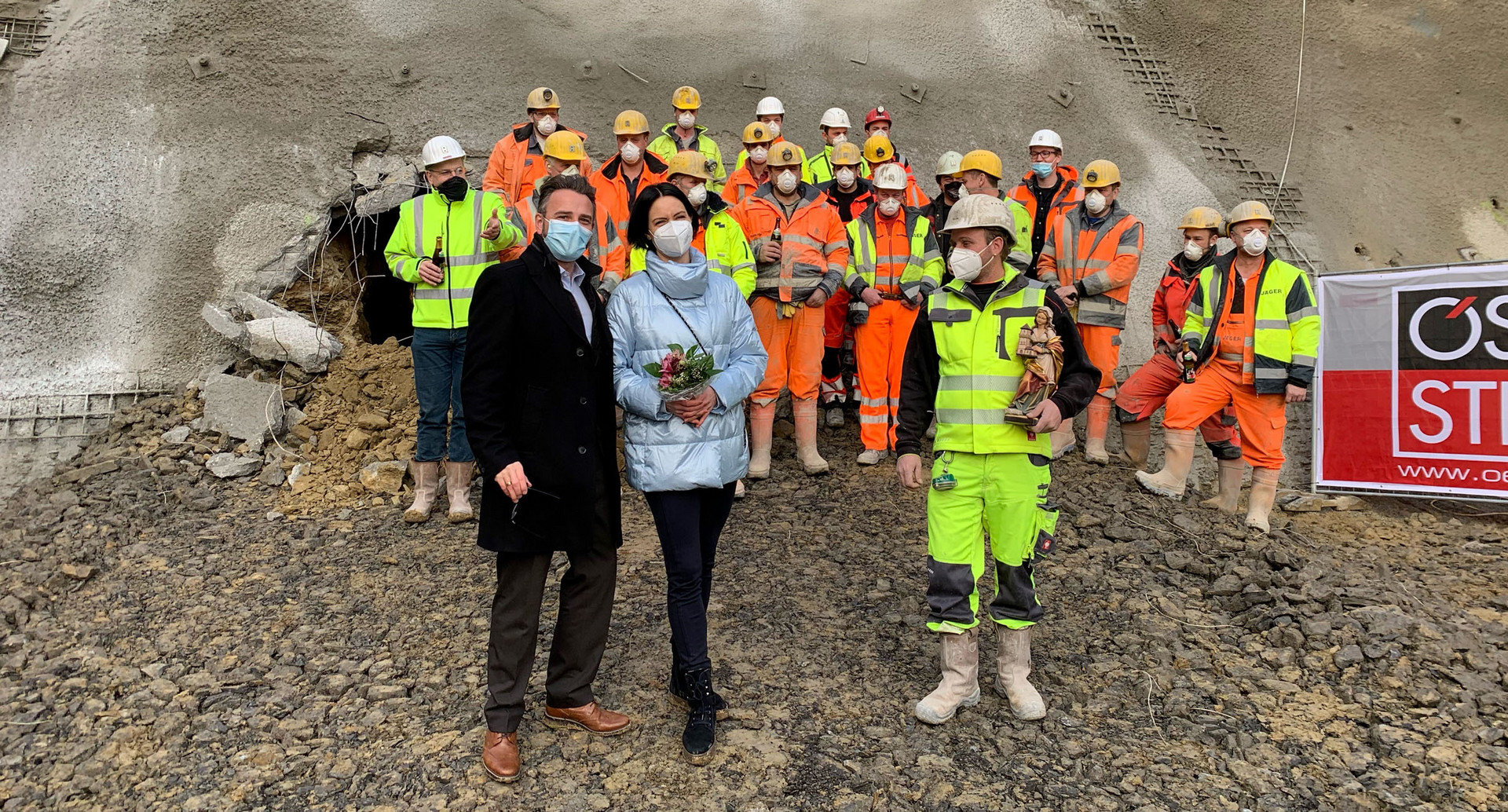 Bauarbeiter stehen vor einem Tunneldurchgang zu einem Gruppenbild zusammen.