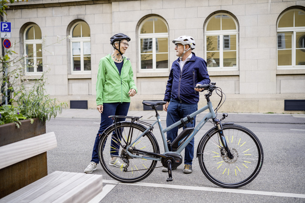 Verkehrsminister Winfried Hermann und Staatssekretärin Elke Zimmer, beide mit Fahrradhelm, stehen neben einem Fahrrad und unterhalten sich.