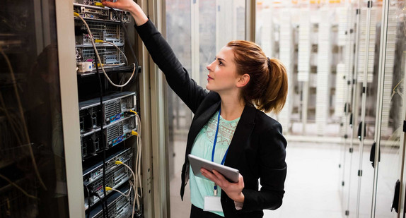 Technikerin hält digitales Tablet während der Untersuchung des Servers