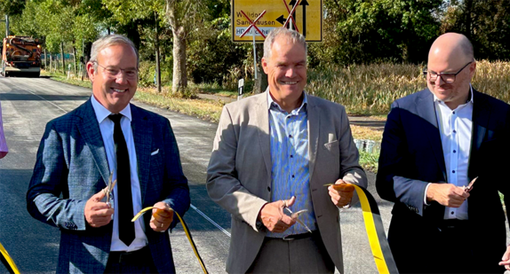 Staatssekretär eröffnet die Straße durch das Schneiden eines Bandes.
