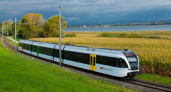 Ein Zug der schweizerischen Bundesbahnen fährt an einem See entlang.