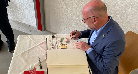 Minister Hermann trägt sich in das goldene Buch der Gemeinde Winden ein.