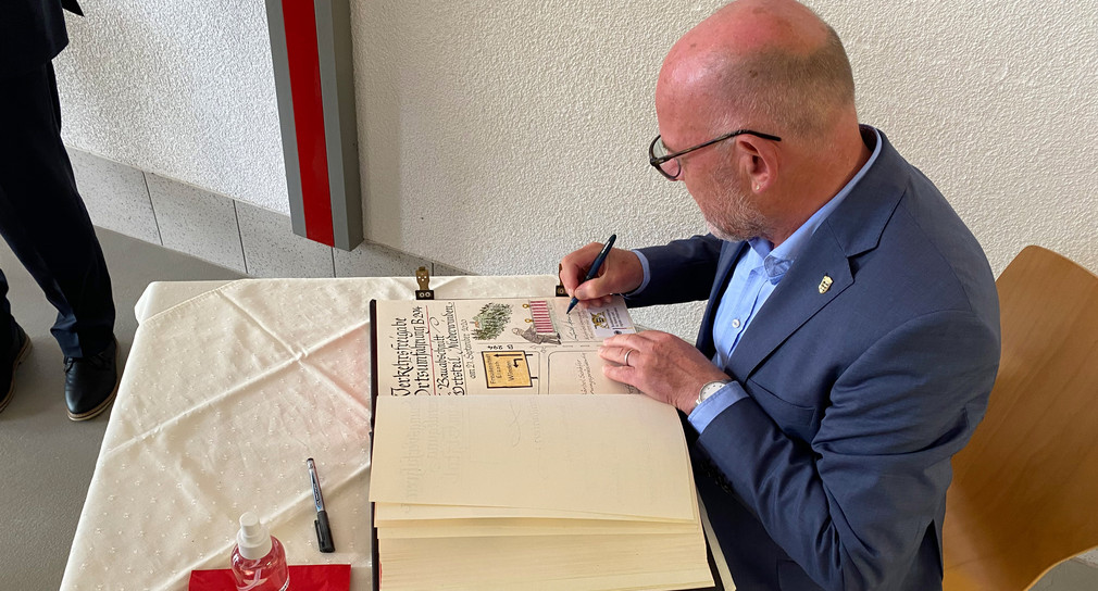 Minister Hermann trägt sich in das goldene Buch der Gemeinde Winden ein.