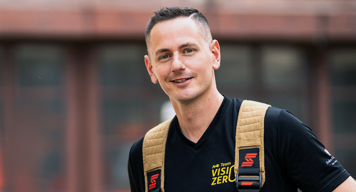 Portrait-Foto von Feuerwehrmann Marco Brand. Unter seiner Einsatzkleidung trägt er ein Team Vision Zero-Shirt.