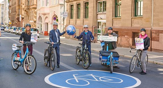 Verkehrsminister Hermann, Amtschef Frieß sowie Mitarbeiterinnen und Mitarbeiter des Landes für den Radverkehr stehen mit verschiedenen Fahrrädern auf einer Fahrradstraße. Hermann und Frieß halten gemeinsam eine Weltkugel.