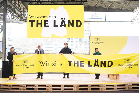 Imagekampagne Baden-Württemberg ist „THE LÄND“ v.l.n.r.: Moderatorin Kimsy von Reischach, Wirtschaftsministerin Dr. Nicole Hoffmeister-Kraut, Ministerpräsident Winfried Kretschmann, Ola Källenius, Vorstandsvorsitzender der Daimler AG, und die Zwei-Sterne-Köchin Douce Steiner halten ein Transparent mit der „Wir sind THE LÄND“.