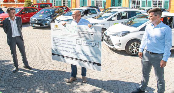 Verkehrsminister Winfried Hermann präsentiert den Scheck für den Rettungsschirm Carsharing. v.l.n.r.: Christoph Erdmenger, Abteilungsleiter im Verkehrsministerium, Verkehrsminister Winfried Hermann, Gunnar Nehrke, Geschäftsführer des Bundesverbands CarSharing e.V.