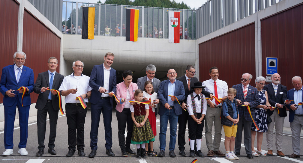 Menschen aus Politik und Bürgerschaft schneiden zusammen mit Kindern ein Band zur Eröffnung des Tunnels durch. 