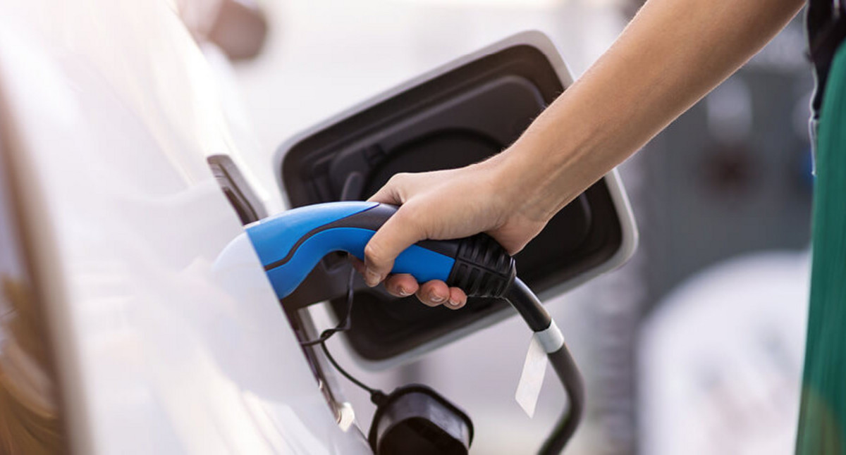 Nahaufnahme: Frau verbindet die Ladesäule mit dem E-Auto