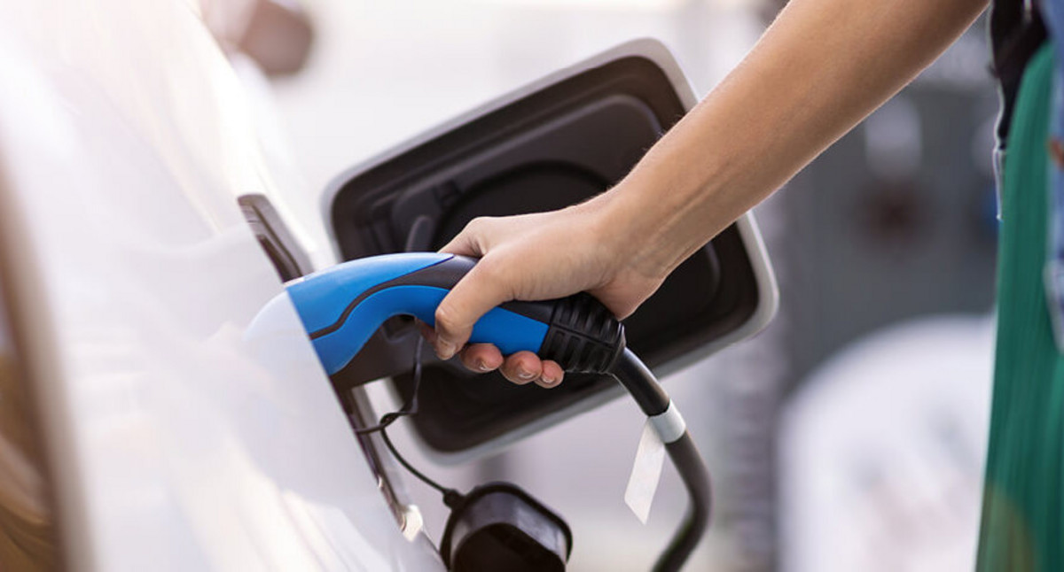 Nahaufnahme: Frau verbindet die Ladesäule mit dem E-Auto