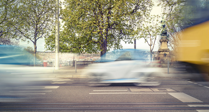 Unscharf gestellte Autos fahren auf einer Straße vorbei.