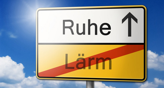 Ein abgewandeltes Ortsschild auf dem das Wort Lärm durchgestrichen ist und ein Pfeil in Richtung des Wortes Ruhe weist. (Bild: Fotolia.com/ K.C.)