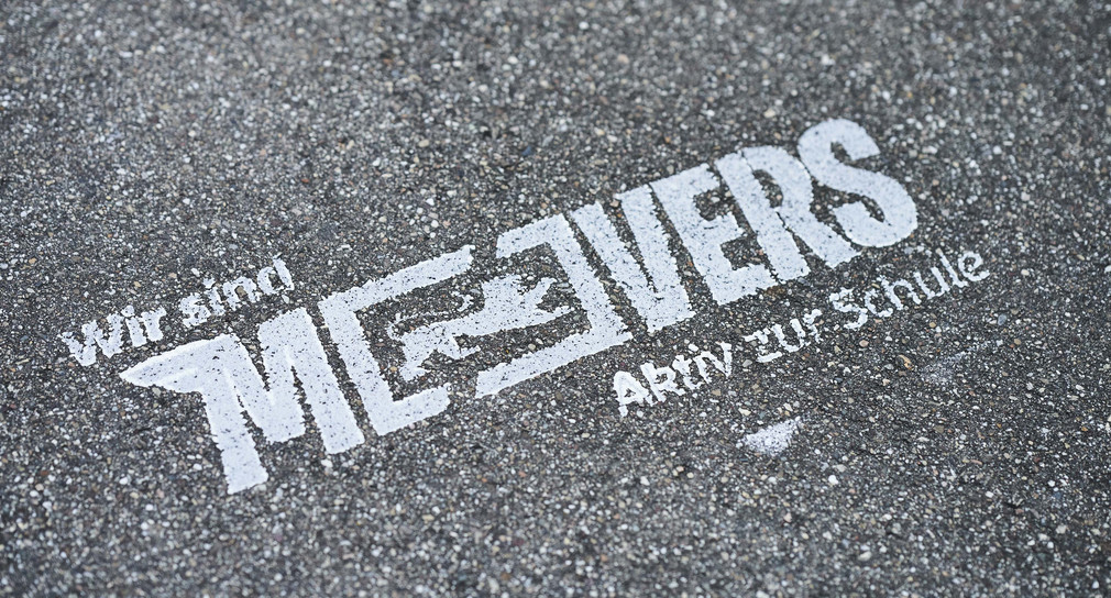 Auf Aspahlt das Logo des Landesprogramms: Wir sind MOVERS – AKtiv zur Schule