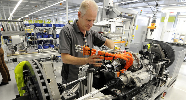 Ein Mitarbeiter montiert im Porsche Werk in Stuttgart-Zuffenhausen eine Vorderachse mit Elektromotor. (Foto: © dpa)']