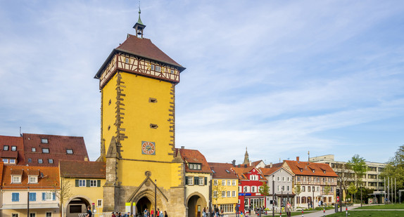 Blick auf mehrere alte Fachwerkhäuser mit einem großen Turm im Mittelpunkt mit einem Durchgang.