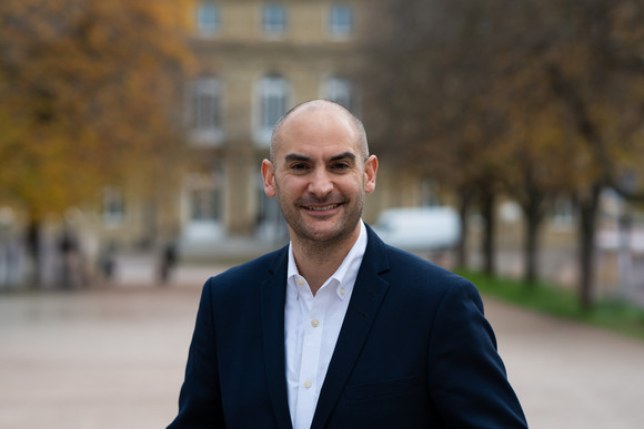 Porträtbilder Minister Dr. Danyal Bayaz Finanzminister Danyal Bayaz am Schlossplatz in Stuttgart, im Hintergrund das Neue Schloss sowie herbstliche Bäume.